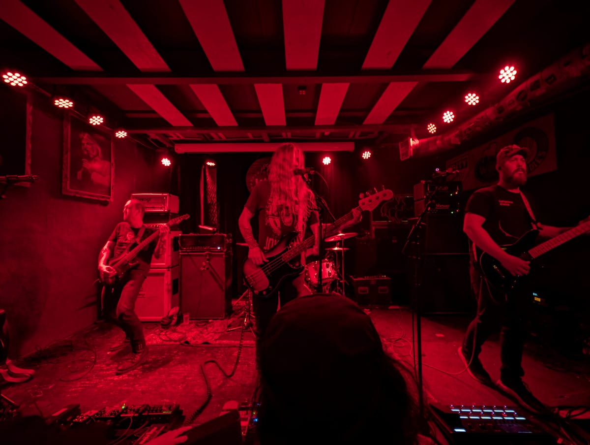 Three guitar players on stage bathed in red light