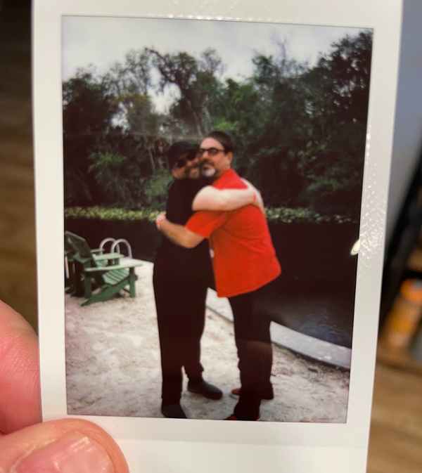 I way-too-small polaroid of two grown men hugging. 