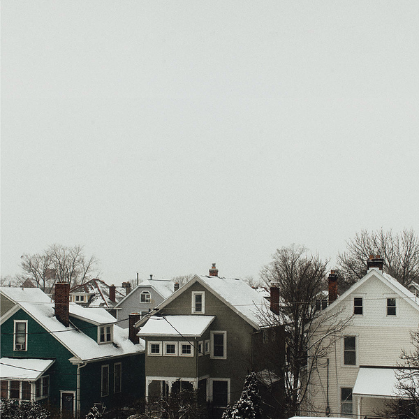 A grey sky with snow covered houses in the lower third of the photo.